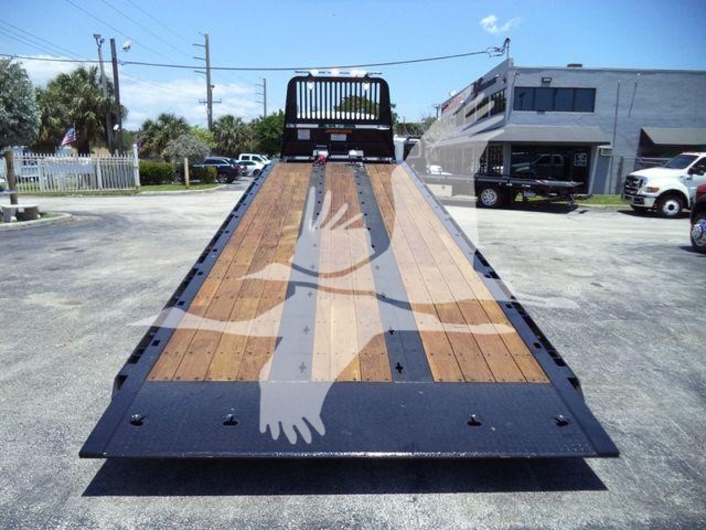 Kenworth T880 rollback flatbed bed with wood planks and black steel frame in daylight.