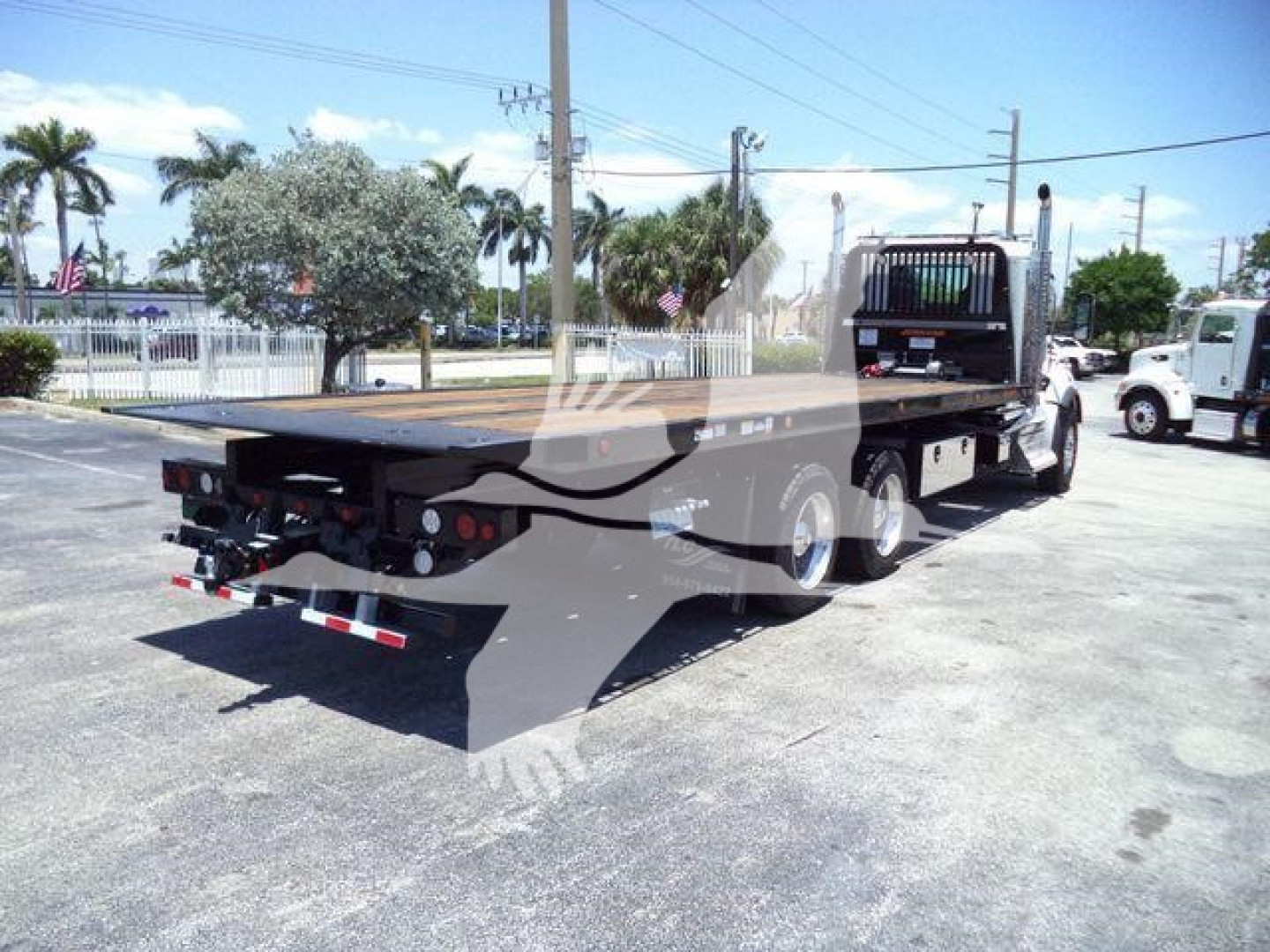 Kenworth T880 rollback truck from rear-left side showing flatbed and dual rear axles with hydraulic controls