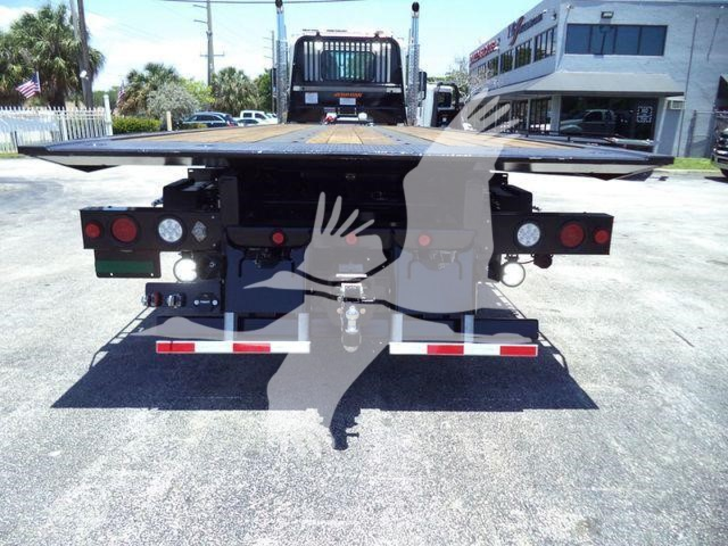 Trailer/rollback equipment rear view showing rear lights, bumper, and platform; Kenworth T880 rollover bed visible in distance.