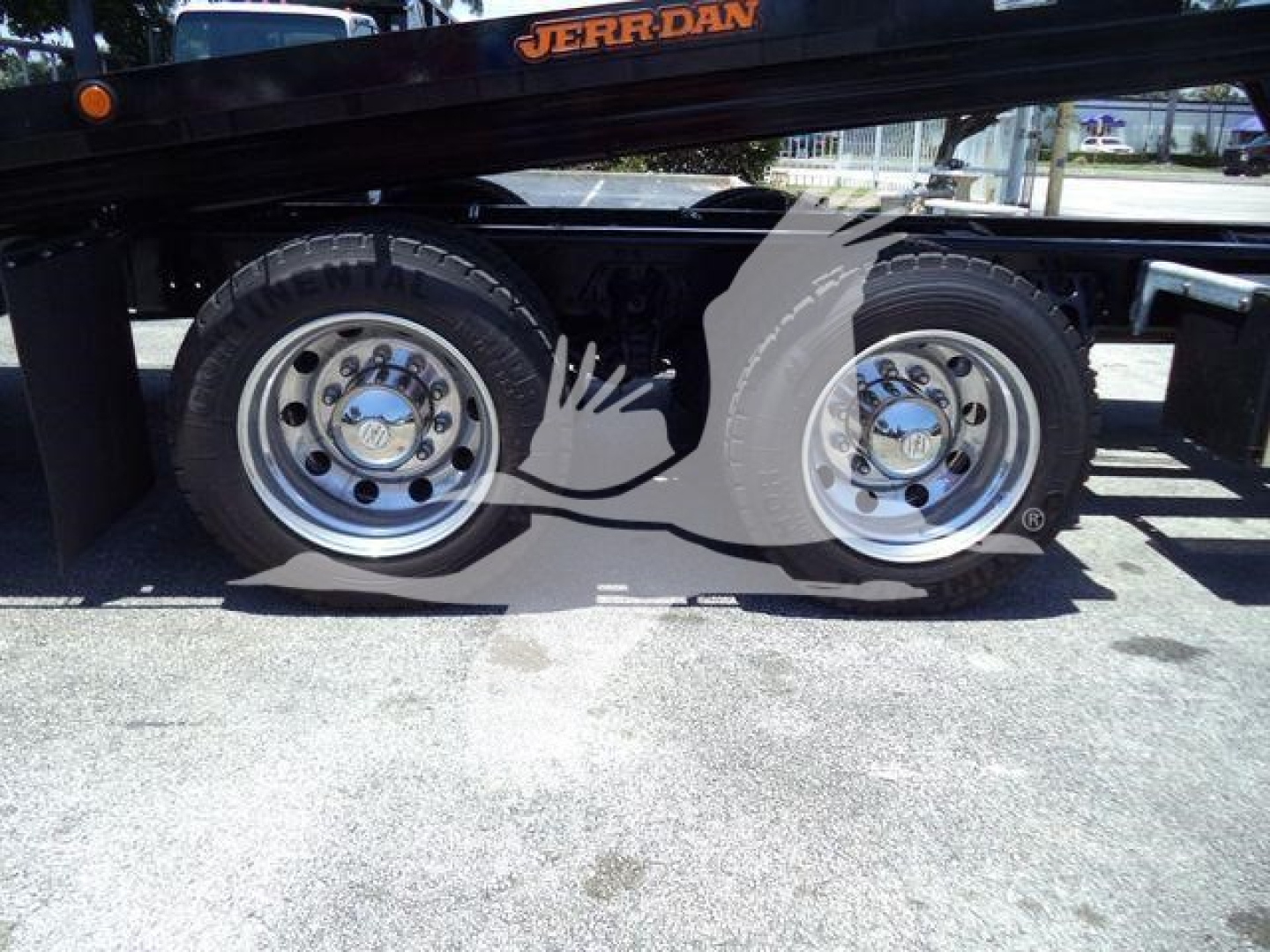Kenworth T880 rollback truck wheel area showing dual rear axles with polished chrome wheels and heavy-duty tires.