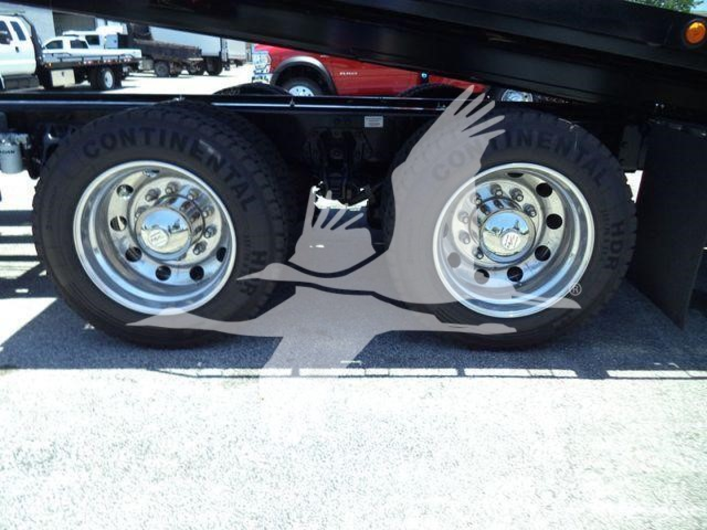 Truck wheel pair on Kenworth T880 rollback, Continental tires with chrome rims, visible undercarriage components.