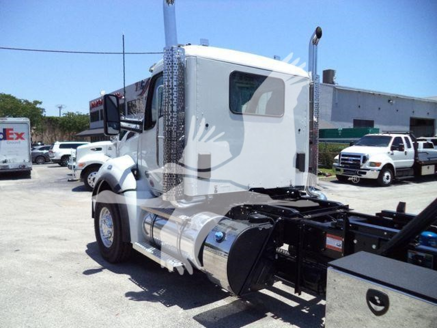 Truck cab side view with large fuel tank and chrome exhaust, rollback chassis visible. Details include a Kenworth-style sleeper cab and rear wheels; no legible serial numbers or labels visible in this crop.