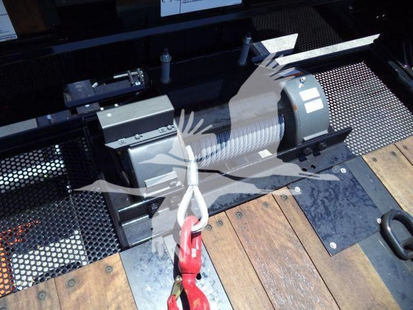 Kenworth T880 rollback truck winch assembly showing electric winch motor and wire rope with hook on wooden deck bed.