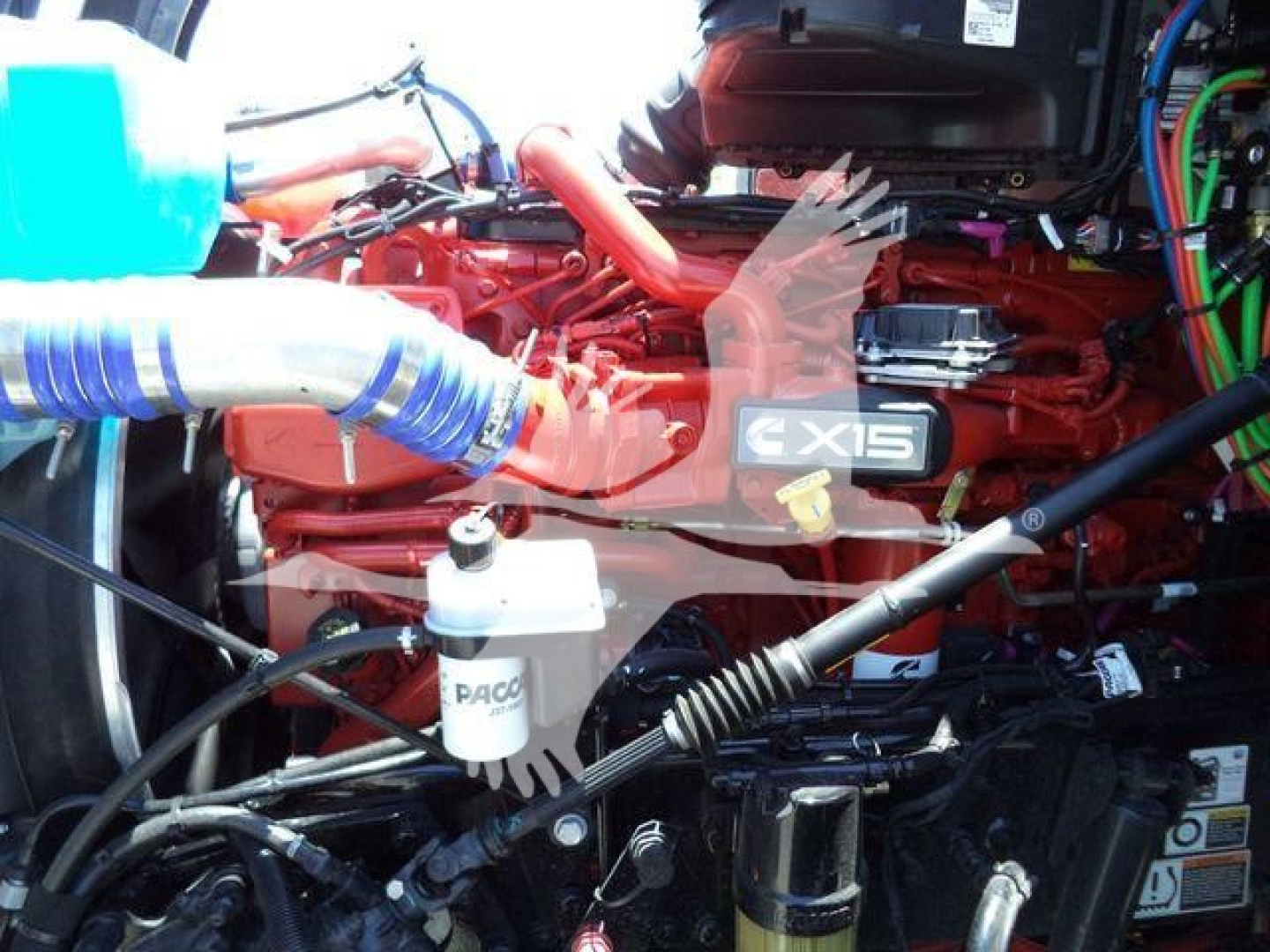 Kenworth T880 engine bay showing X15 badge and various hoses and components including coolant reservoir and filters.
