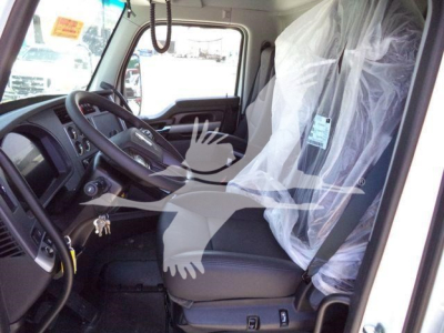 Kenworth T880 truck cabin interior view showing driver's seat, steering wheel, and protective plastic covering on the passenger seat; dashboard and side window visible.