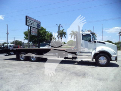 Kenworth T880 rollback truck side view showing long flatbed and chrome cab with wheel assembly.