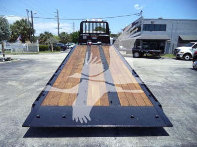 Kenworth T880 rollback flatbed bed with wood planks and black steel frame in daylight.