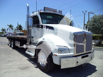 Kenworth T880 heavy duty truck in white with flatbed rollback configuration, front grille, chrome bumper, and large side mirrors.