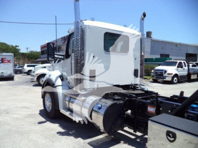 Truck cab side view with large fuel tank and chrome exhaust, rollback chassis visible. Details include a Kenworth-style sleeper cab and rear wheels; no legible serial numbers or labels visible in this crop.