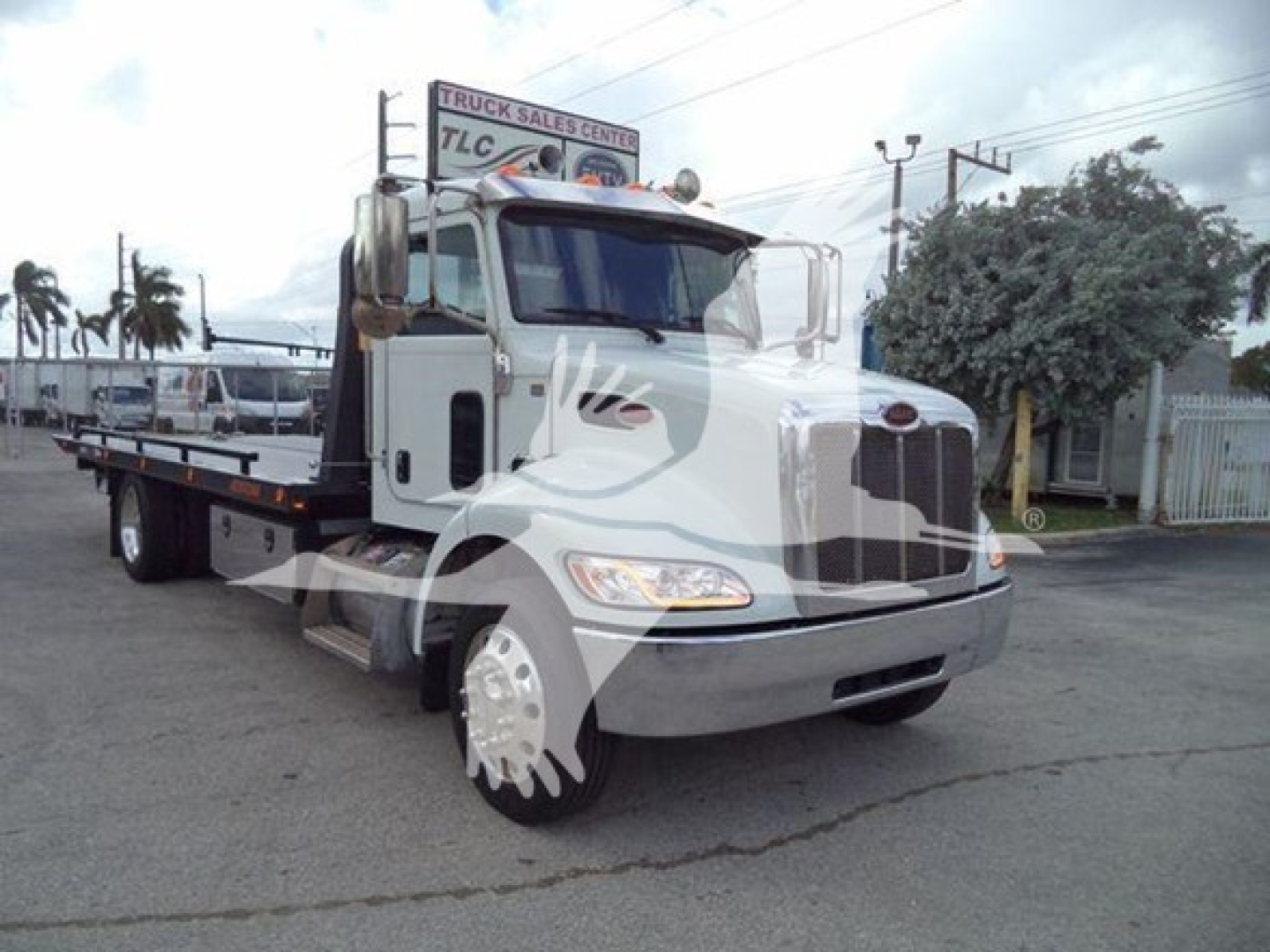 2019 Peterbilt 337 rollback truck shown in a side/front view with white cab and flatbed. Visible text on truck: Peterbilt emblem on grille.