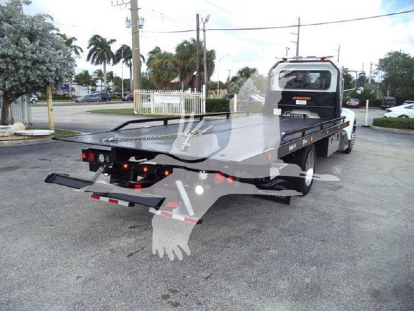 Peterbilt 337 rollback truck showing flatbed with rear loading ramps and cab in view.