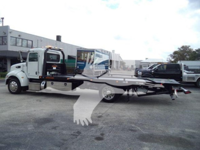 Peterbilt 337 rollback tow truck side view showing flatbed and crane, VIN plate area not legible, service yard background.