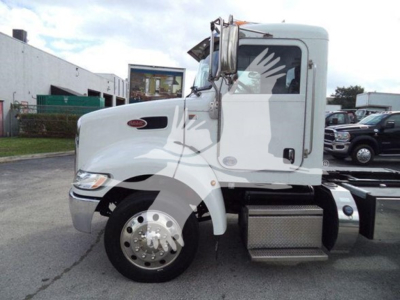 Peterbilt 337 rollback truck side view with white cab and chrome steps, badge on front fender, VIN 2NP2HM6X0KM499359 visible in listing, storage area and other vehicles in background.