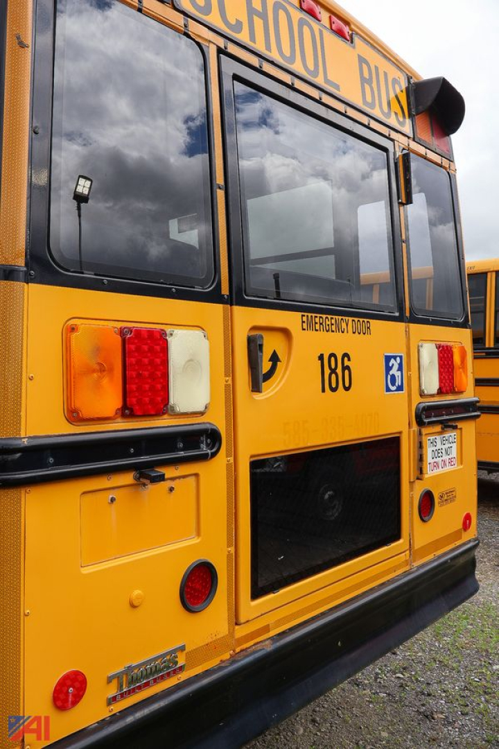 Back view of a yellow Freightliner C2 school bus showing emergency door, bus numbers 186 and handicapped placard, rear lights.