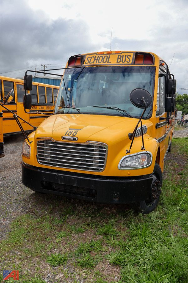 School bus front view showing yellow Freightliner C2 Saf-T-Liner with 'SCHOOL BUS' sign and large grille.