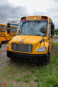 School bus front view showing yellow Freightliner C2 Saf-T-Liner with 'SCHOOL BUS' sign and large grille.