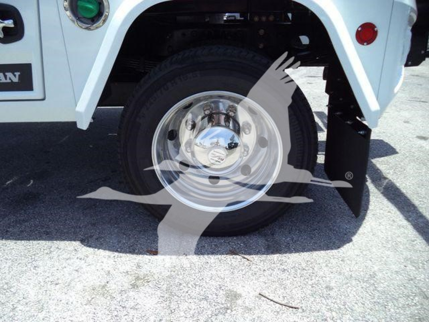 Truck wheel and fender showing chrome hubcap and partial body with winch category vehicle.