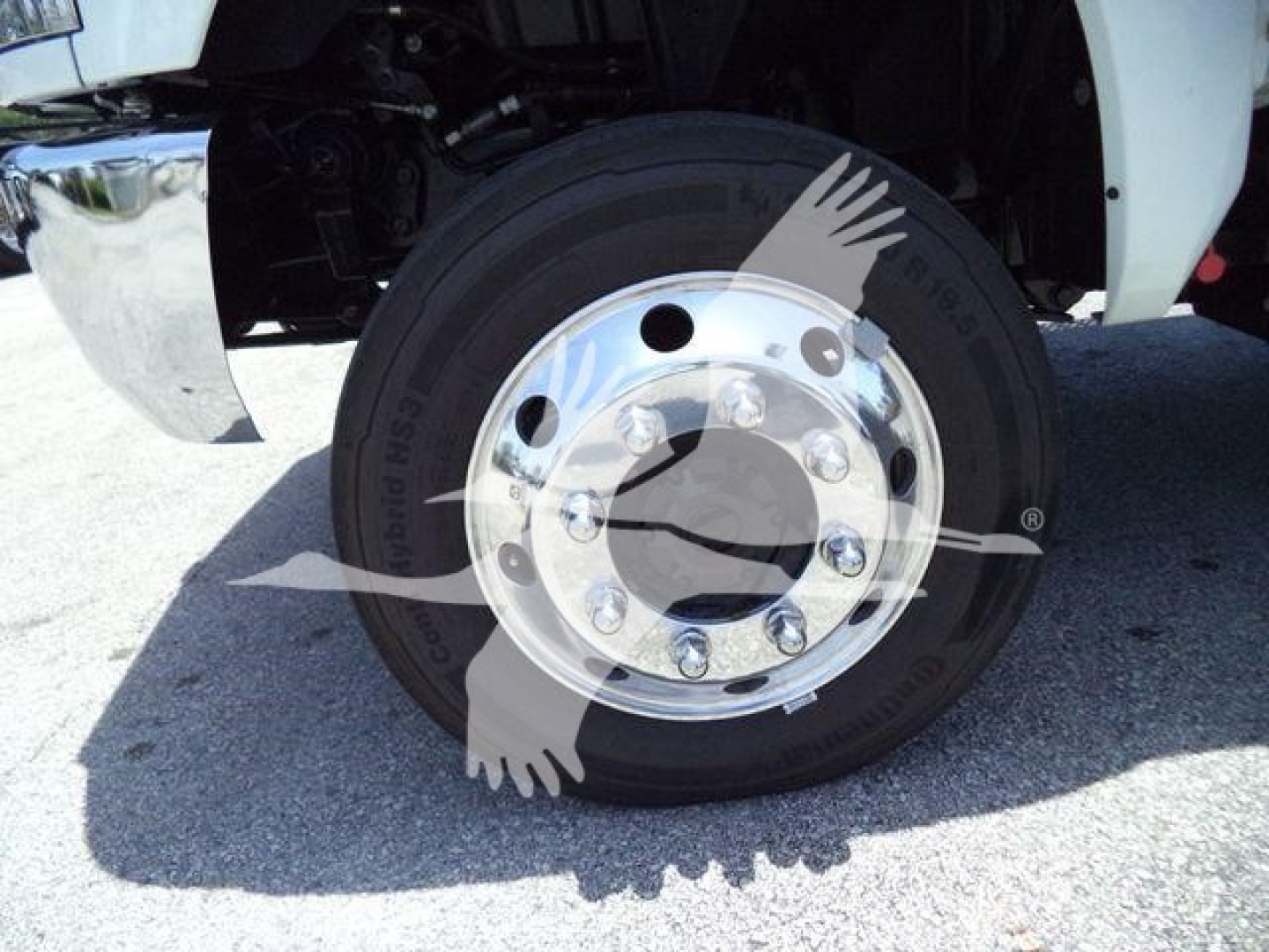 Truck wheel with polished chrome hub and black tire, part of a winch-equipped International CV truck.