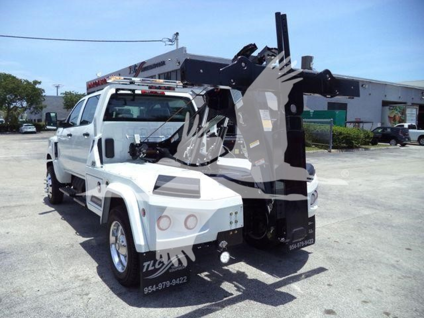Truck-mounted crane/winch unit on a white International CV truck, side view, with hydraulic arms extended and control cabin visible.