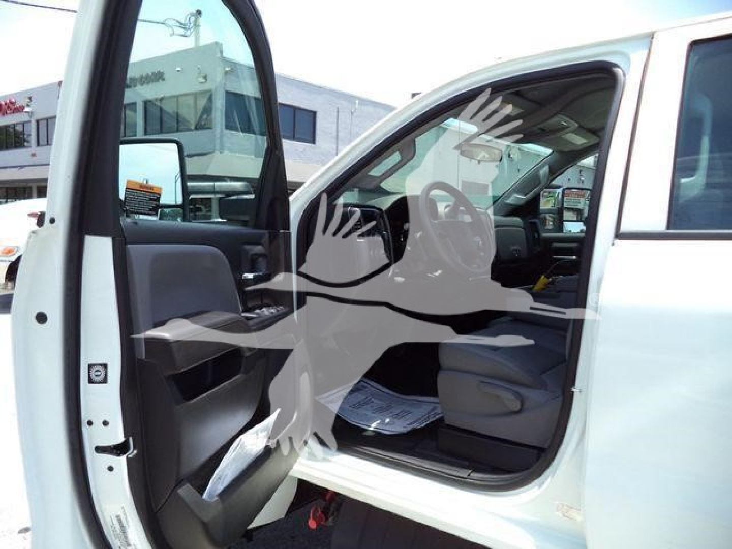 Truck cab interior with front door open, steering wheel visible, documents on seat, and exterior white paint