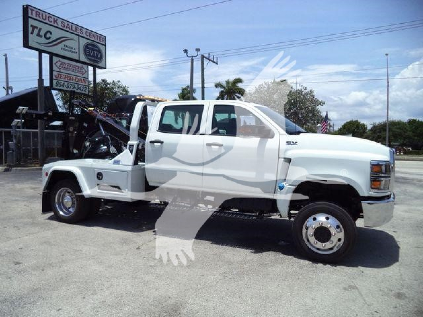 Truck with tow winch setup in front of a dealership lot, white cab and dual rear wheels, stock number J19799FM, category Winch, type Trucks.