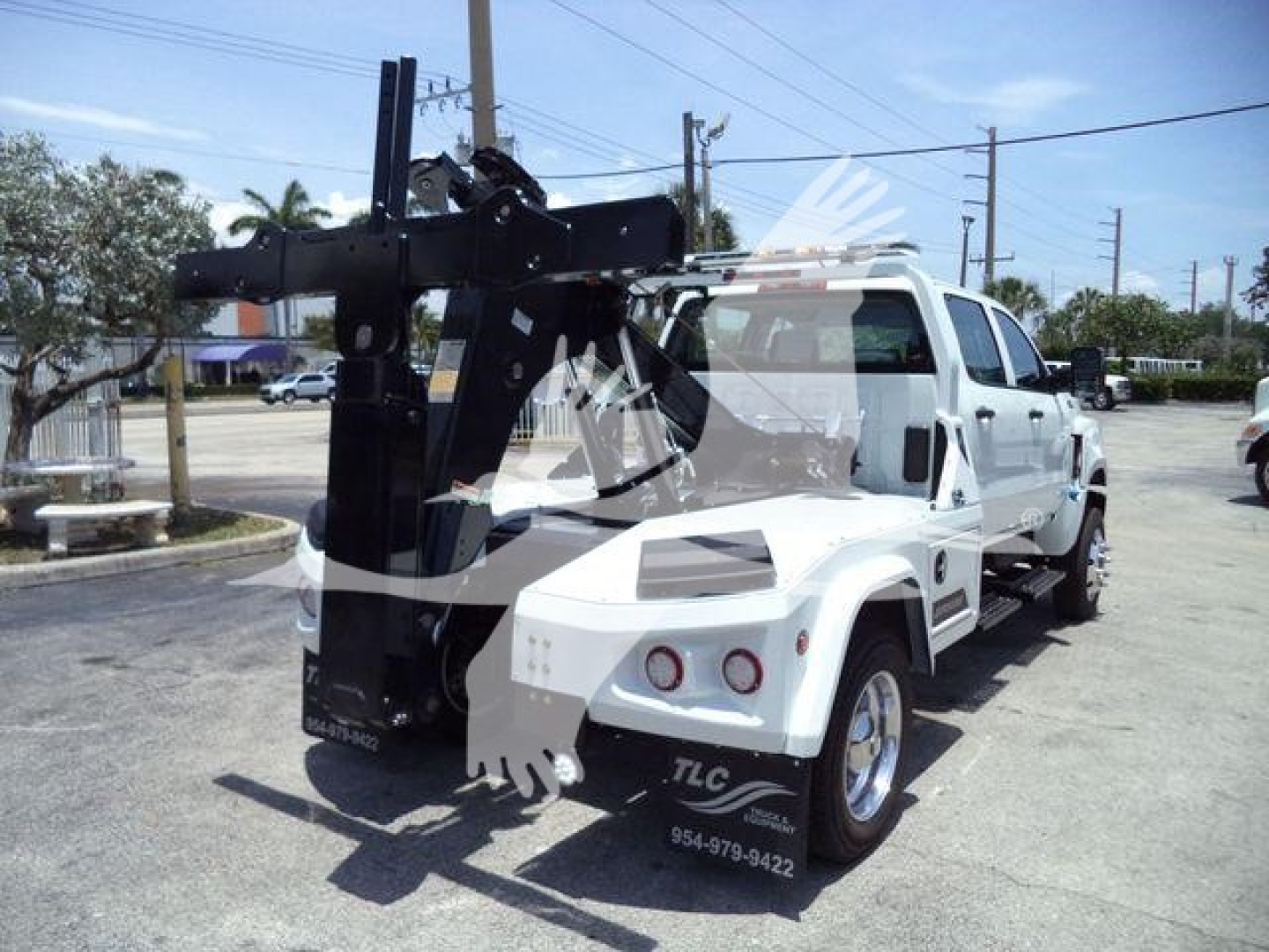 Tow truck with heavy-duty winch arm mounted on front, white exterior, side mirrors, street in background, stock number J19799FM.