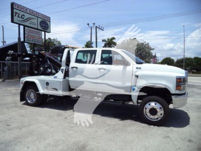 Truck with tow winch setup in front of a dealership lot, white cab and dual rear wheels, stock number J19799FM, category Winch, type Trucks.