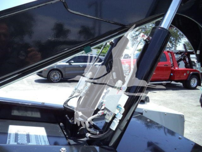 Winch-equipped truck cab with hydraulic lines and control components visible, tilted open to show internal mechanism.