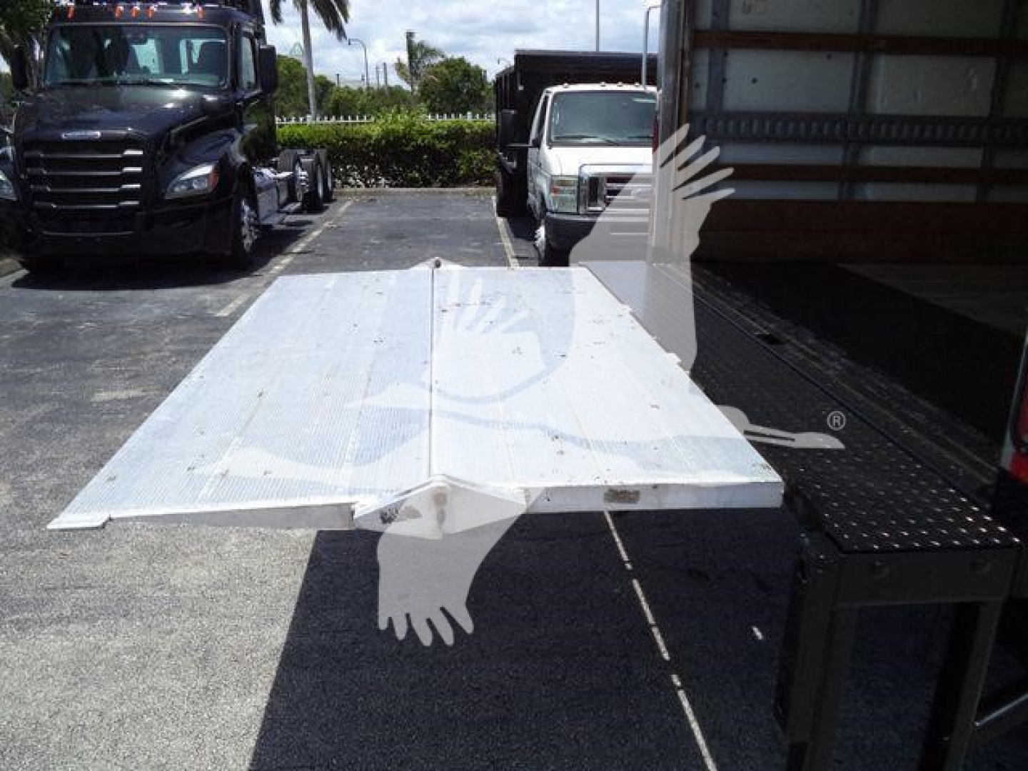 Flatbed tow truck bed in open lot with Isuzu NPR HD