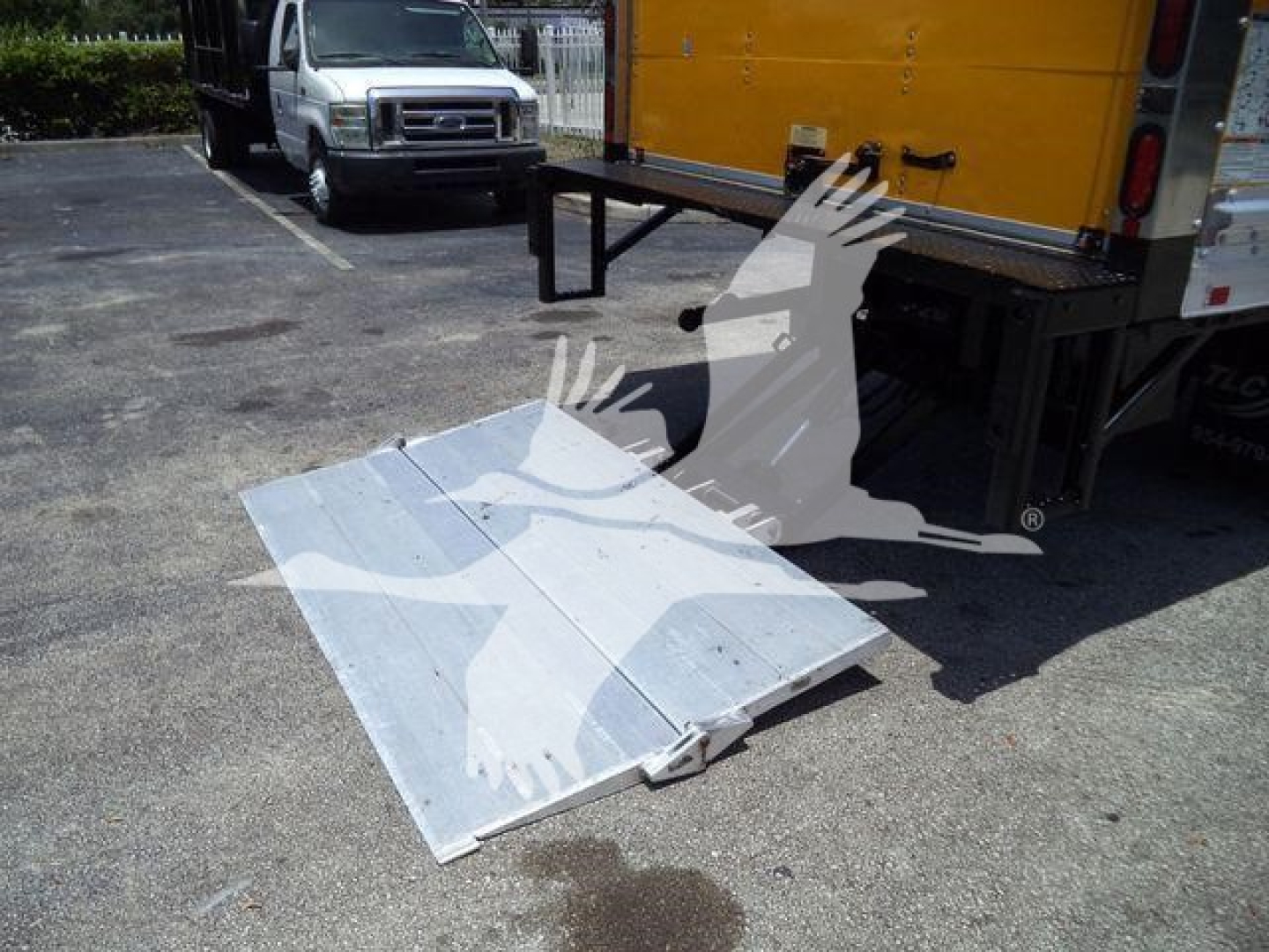 Isuzu NPR HD truck bed ramp/tilt plate attached to rear with metal ramp laid flat on ground