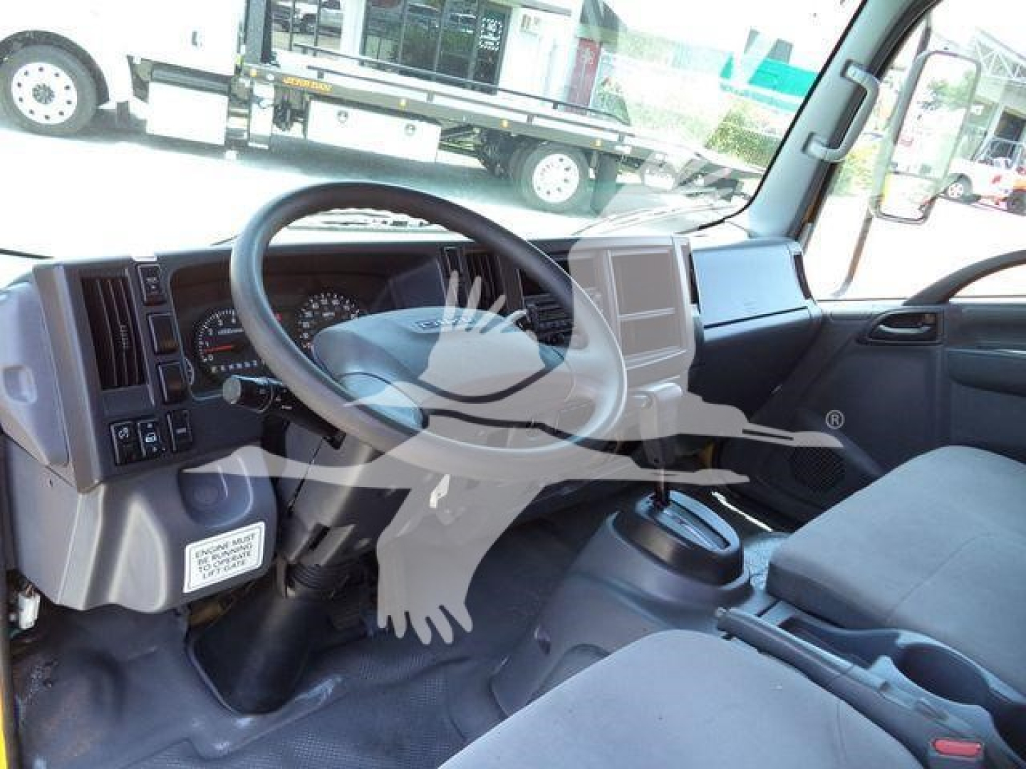 Isuzu NPR-HD truck interior showing steering wheel, dashboard, and driver seat with center console and gauges.