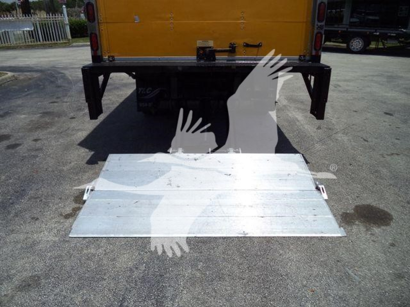 Isuzu NPR HD truck rear with tailgate lowered showing aluminum ramp/platform on ground.