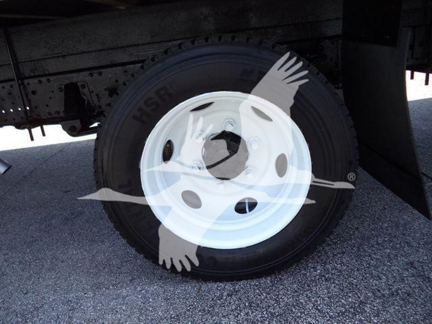 Isuzu NPR HD truck wheel and white steel rim showing a compact spare hub and tire with surrounding undercarriage in view.