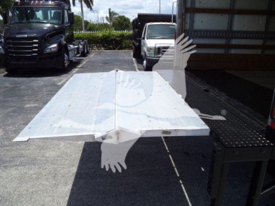 Flatbed tow truck bed in open lot with Isuzu NPR HD