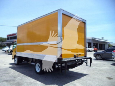 Isuzu NPR HD box truck seen from rear-left exterior showing yellow cargo box and rear kick plate