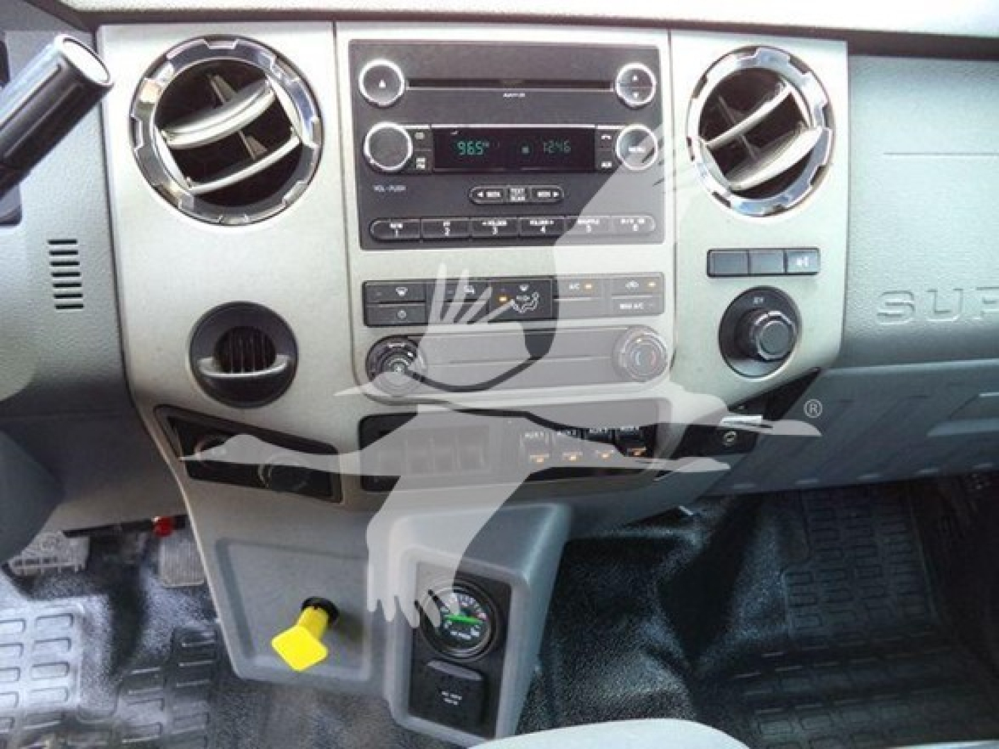 Dashboard view of a Ford F-Series truck showing center console with radio, climate controls, circular air vents, and a green 12V accessory plug.