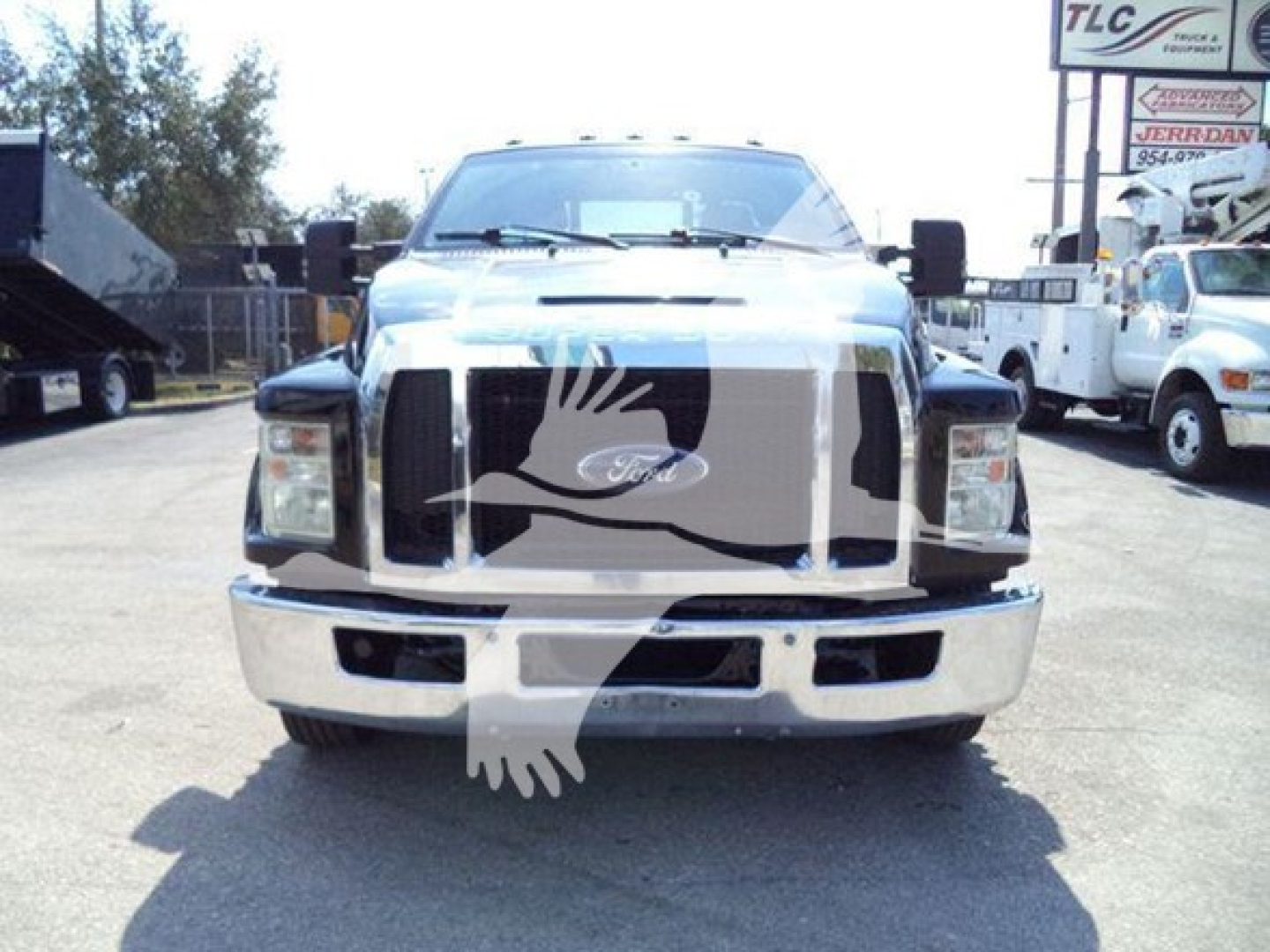Ford F-650 semi/rollback front view showing large chrome grille, bumper, and headlights with a watermark overlay from the photo; no legible model or specs visible on the body in this view.