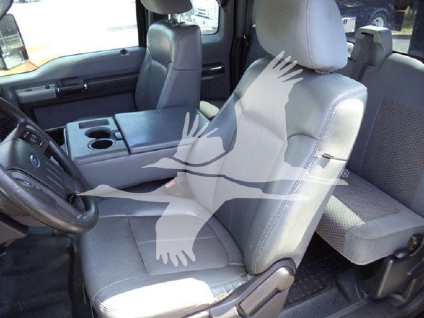 Interior of a Ford F-650 rollback cab showing front seats, center console with cupholders, steering wheel, and back seat visible.