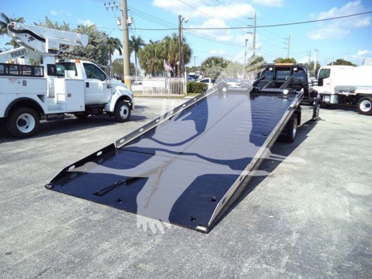 Ford F650 rollback truck with a tilted flatbed in a truck lot.