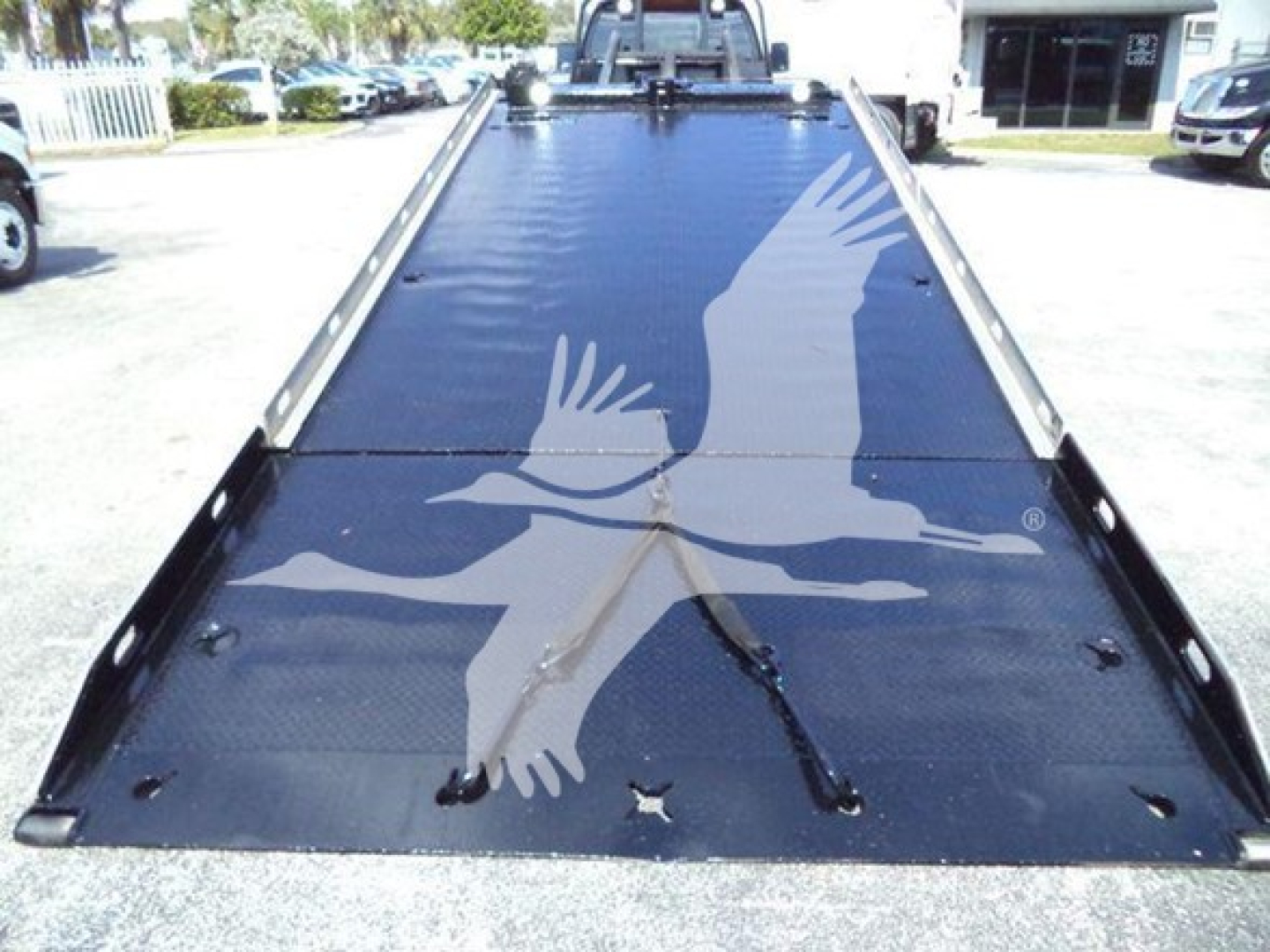 Ford F650 rollback flatbed truck bed showing black metal surface with tie-downs and side rails.