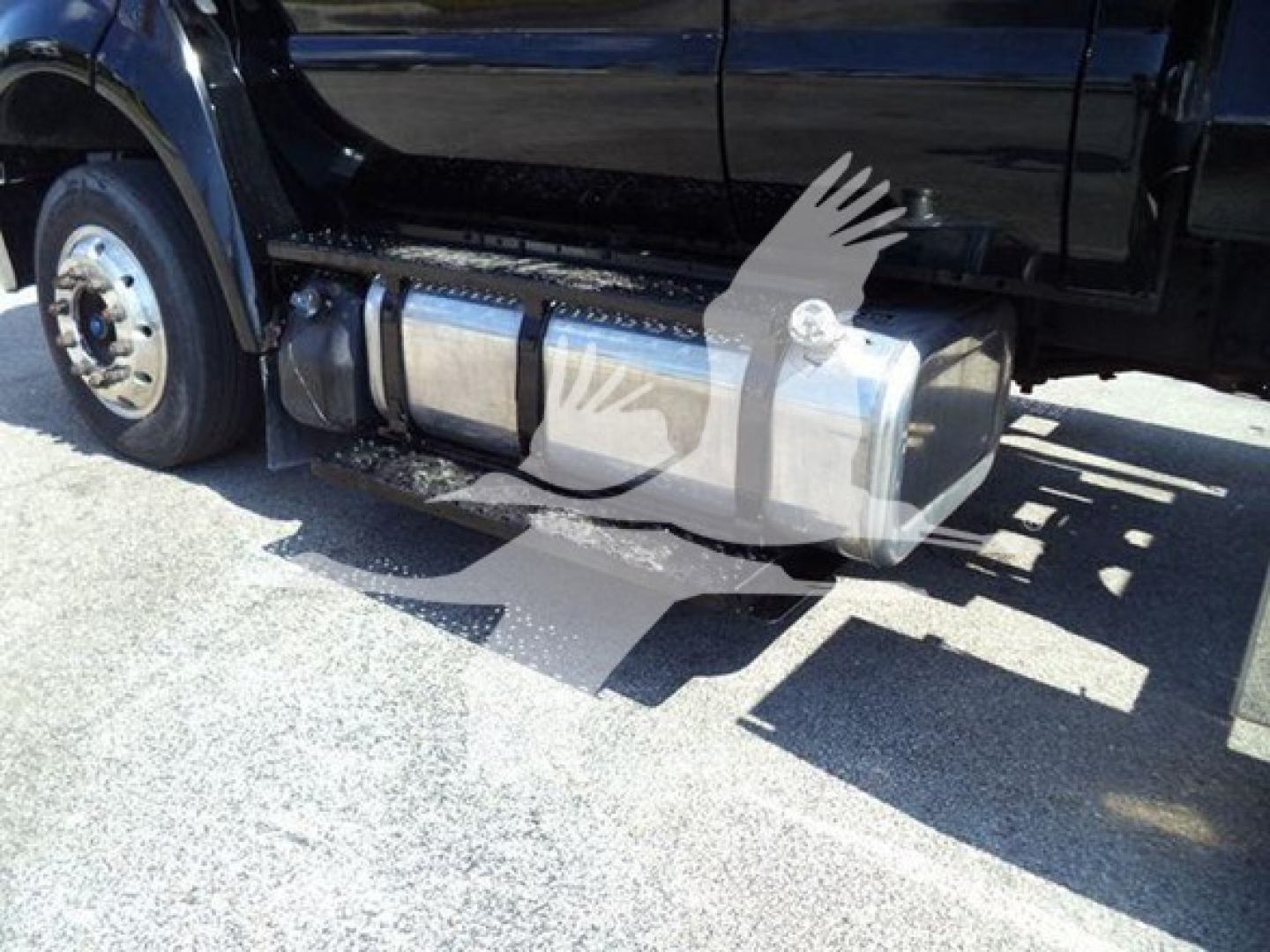 Truck side view showing fuel tank and underbody components near the cab on a Ford F-650 rollback.