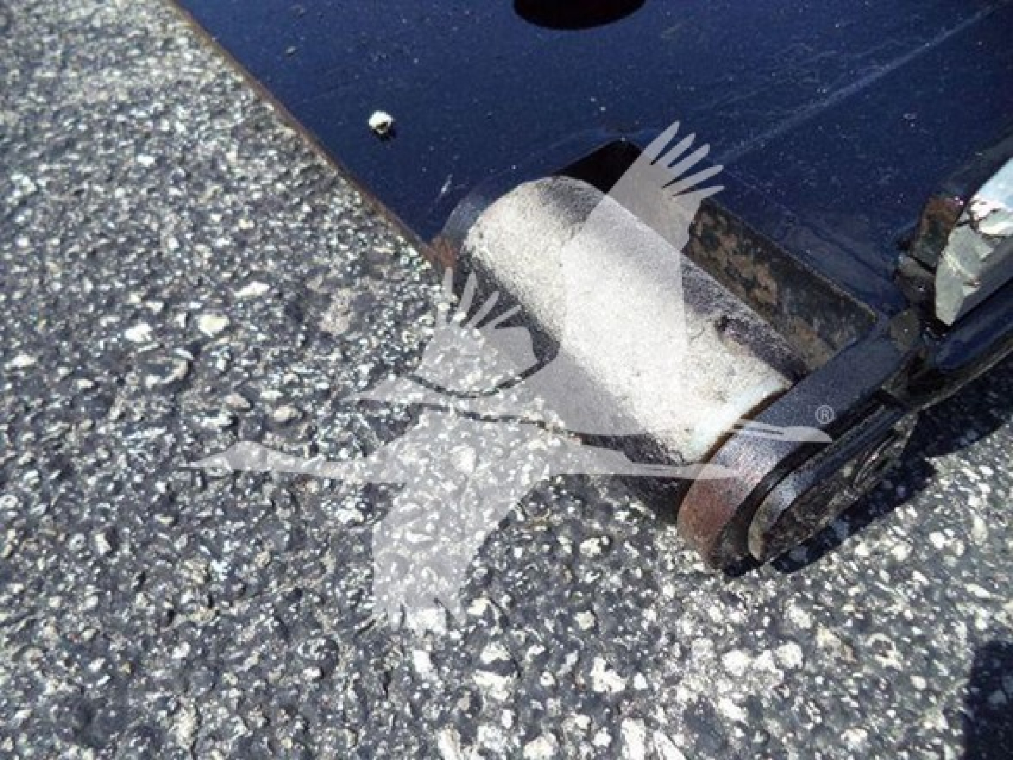 Ford F-650 rollback truck hitch and wheel area visible; metallic hitch components and ground texture.