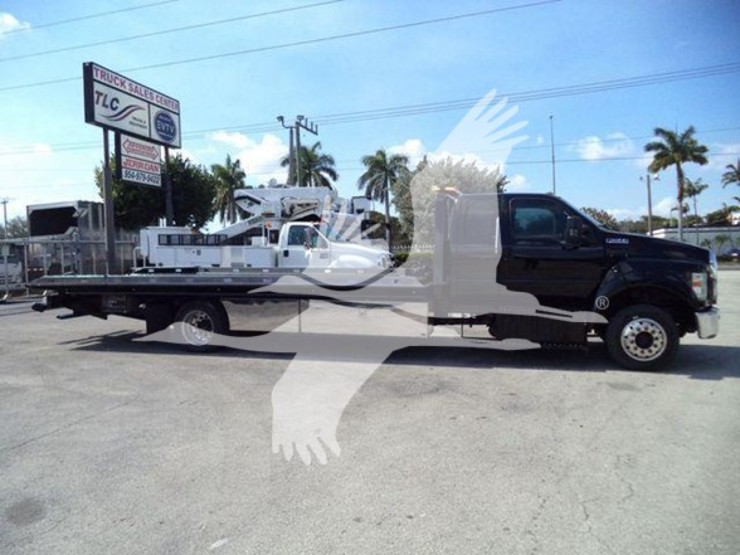 Ford F650 rollback truck visible in side profile with flatbed and towing chassis.