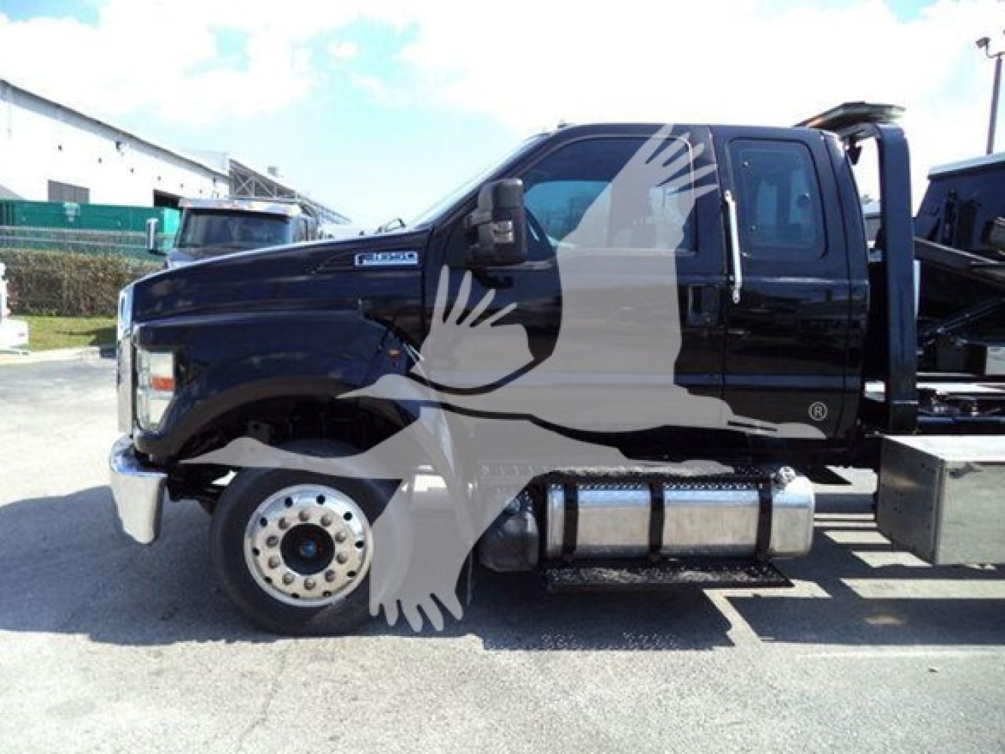Ford F650 rollback truck side view showing dual rear wheels, black cab, chrome bumper, and fuel tanks visible under cabin.
