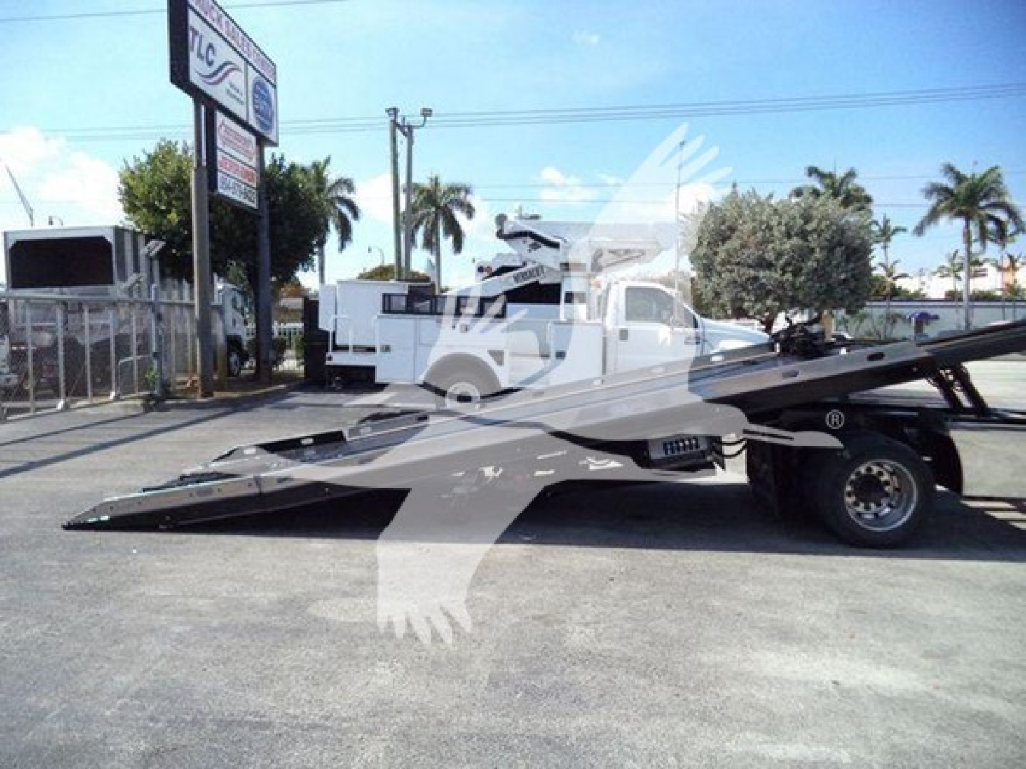 Flatbed rollback tow truck on lot with front view showing Ford F650 with extended wheelbase and hydraulic bed.