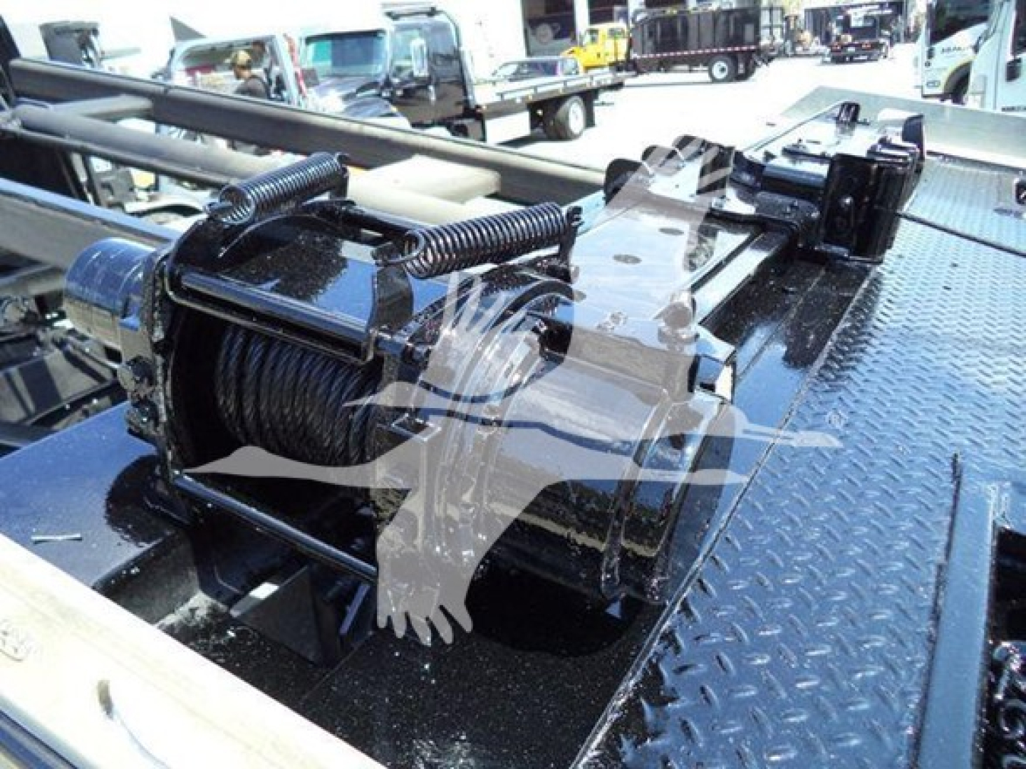 Truck bed winch reel and hydraulic hook system on a Diamond plate surface, with coiled steel cable and winch motor visible.