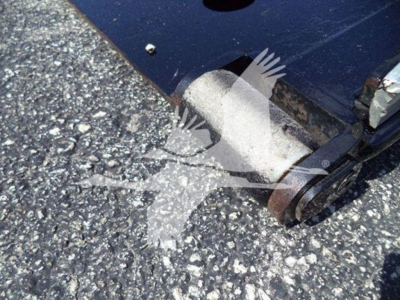 Ford F-650 rollback truck hitch and wheel area visible; metallic hitch components and ground texture.