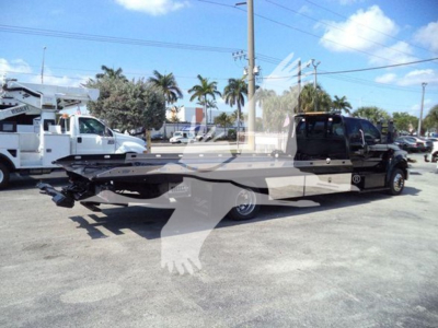 2017 Ford F650 rollback truck in a dealership lot showing flatbed bed and towing setup.