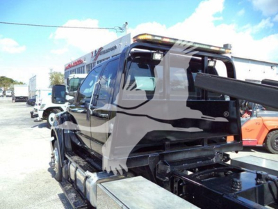 Ford F650 rollback truck with extended cab view from rear side showing tow setup and fuel tanks.