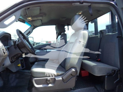 Truck cab interior showing front bench seat and driver's seat, steering wheel, dashboard, and gray interior. Windows reveal partial exterior equipment.